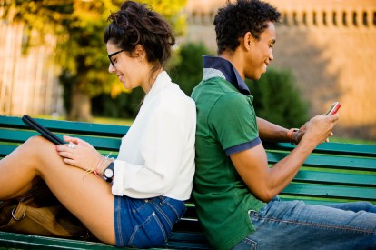 Happy Young Italian Couple using Digital Tablet and Mobile Phone